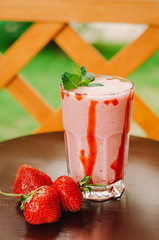 Fresh cold milk cocktail with strawberries on wooden background. Copy space