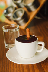 Hot chocolate in a white ceramic cup on a wooden table. Morning homemade coffee. Relaxing time concept. Copy space. Selective focus.