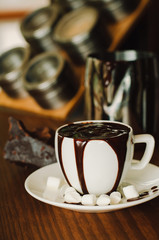 Hot chocolate in a white ceramic cup on a wooden table. Morning homemade coffee. Relaxing time concept. Copy space. Selective focus.