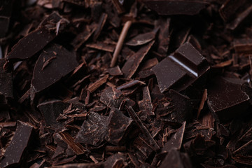 Tasty crushed dark chocolate as background, closeup