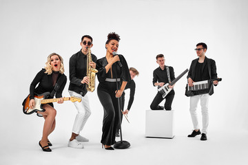 photo of multi ethnic music band in studio.Musicians and woman soloist posing over white background