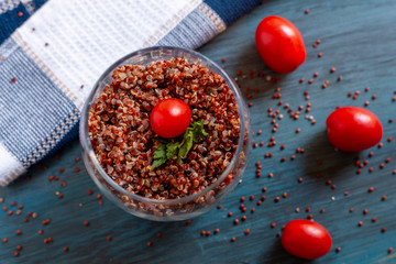 Red quinoa salad with tomato on a rustic table. Superfood and healthy eating concept.