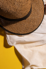 sombrero de playa cafe sobre salida de baño blanca y fondo amarillo