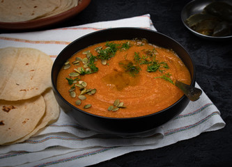 Amaranth and carrot polenta in black bowl served with corn tortillas