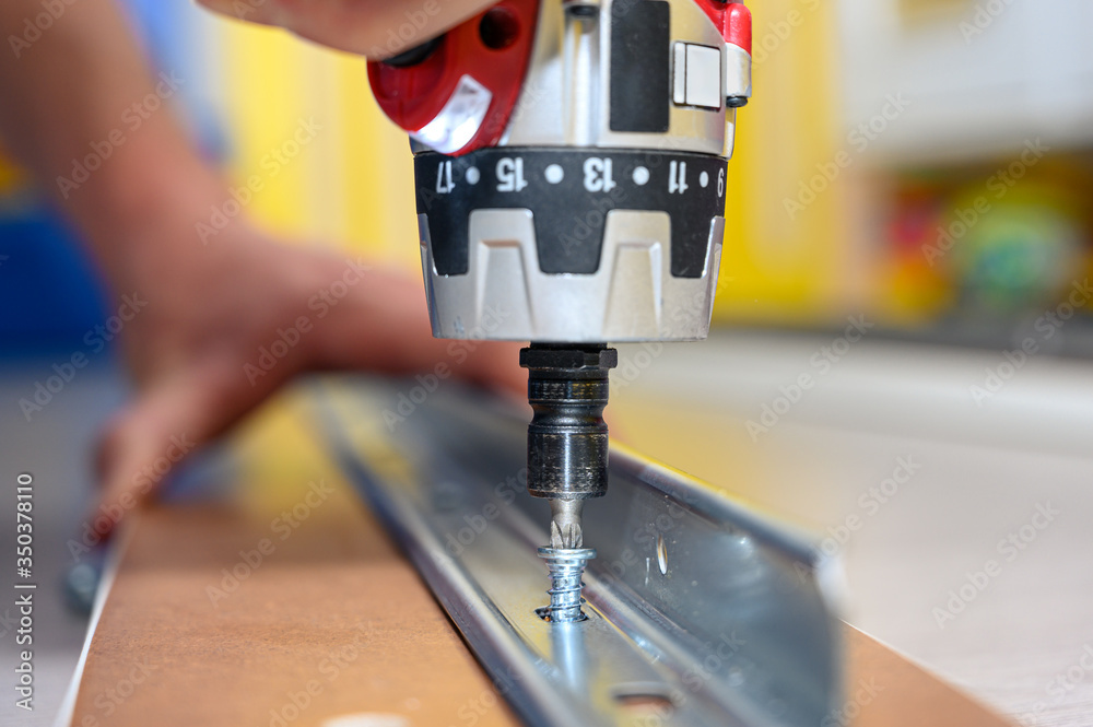 Wall mural man using an electric screwdriver to assemble a piece of furniture from a famous swedish store