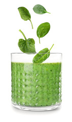Fresh green spinach leaves falling into glass with smoothie on white background