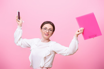 Smiling young woman in glasses holds a folder and a mobile phone in her hands. Concept of female business and customer calling