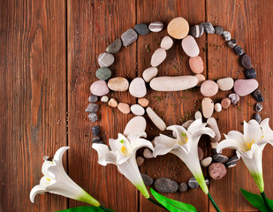 Pentagram made of stones with white flowers on a wooden background. Top view.