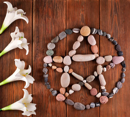 Pentagram made of stones with white flowers on a wooden background. Top view.