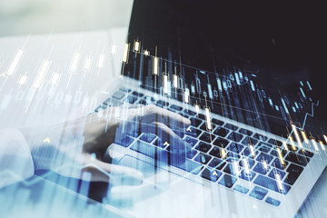 Abstract creative financial graph with hand typing on laptop on background, forex and investment concept. Multiexposure