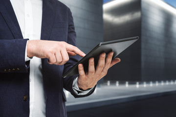 Man using digital tablet near the exterior of the business center at night, close up. Technology concept