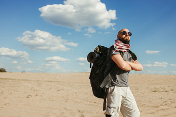 Travel, trekking concept. Touristic lifestyle. Man with backpack hiking. Tourist traveling through the desert