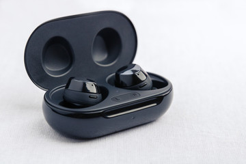 An opened black wireless earbud charging case - Front side angled view.