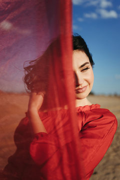 Beautiful Woman In Silk Red Dress Close Up Portrait In Sand Desert Dunes. Fashion, Beauty Concept