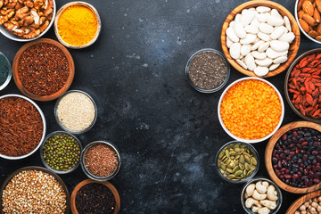 Superfoods, legumes, nuts, seeds and cereals selection in bowls on grey background. Superfood as chia, spirulina, beans, goji berries, quinoa, turmeric, mung bean, buckwheat, lentils, flax seed