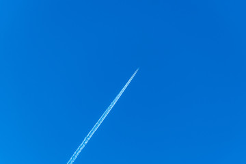 An airplane flying high in the clear blue sky leaving white streaks