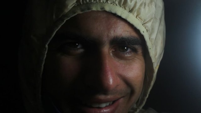 A young man smiling in a slightly dark place