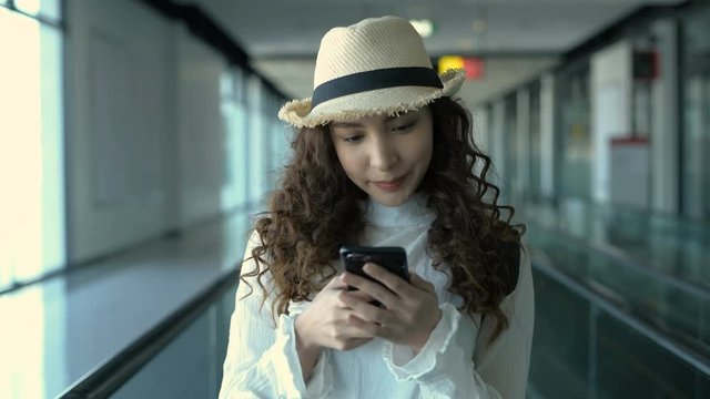 Travel concept. A girl playing on the phone while traveling at the airport. 4k Resolution.