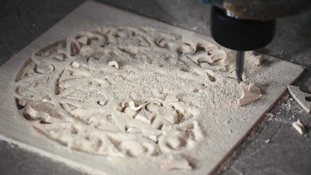 Extreme closeup of a CNC machine routing maple wood plank for cutting off an oud / guitar hole cover cage