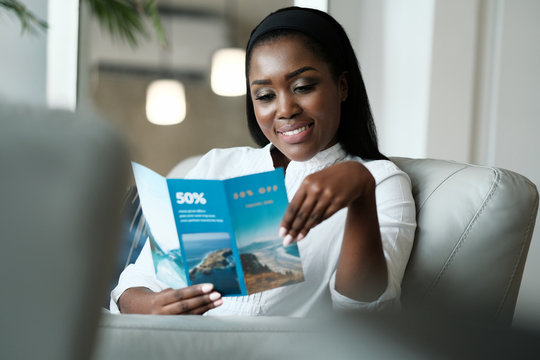 Black Woman Reading Travel Flyer For Holiday Trip