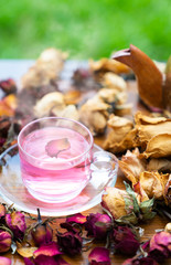 Organic tea rose made from tea  rose petals in a glass bowl on the wooden rustic background around with dry rose petals