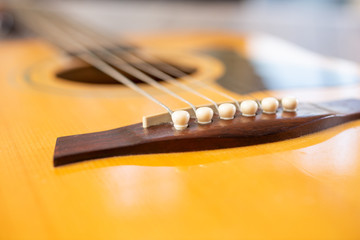 A view of the pegs that hold the strings of an acoustic guitar.