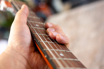 A closeup view of a hand holding the fretboard, created chord finger positions, on an acoustic...