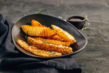 Homemade organic French fries with pink salt and cranberry sauce on black background.