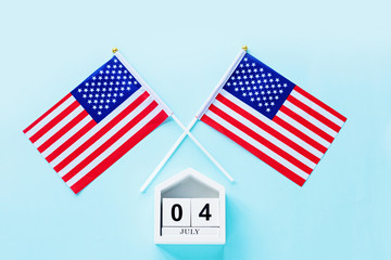Obraz premium July 4th. Mockup of july 4 wooden color calendar and USA flag on blue background. Copy space for text. Independence Day Of America. Flat lay, top view, template