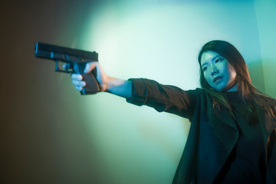 cinematic portrait of young attractive and dangerous special agent woman spy or Asian Korean mobster girl holding handgun pointing the gun fierce in Hollywood style