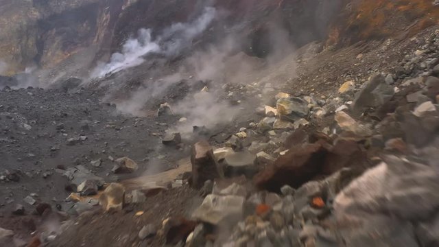 Close up of stones, rocks and ash with gas in crater of volcano