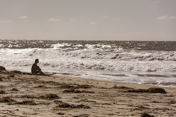 Surfer contemplates the ocean waves in Southern California, 2018