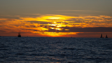 Fototapeta na wymiar reddish sunset on the beach full of orange clouds and the sun in the background
