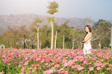 Fototapeta na wymiar happy young woman enjoying summer in zinnia field. Beautiful woman relaxing in pink flower garden.