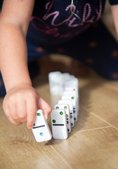 childs hand playing with dominos