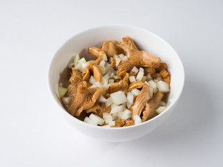 Marinated mushrooms Redheads in a white bowl with onions and vegetable oil. Side view