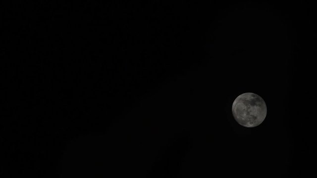 Time lapse motion Craters on the Surface of The full moon In the dark sky and the black clouds at night Moving up fast.
