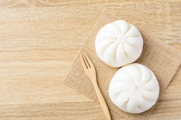 Steamed buns stuffed with minced pork and fork on wooden background, Asian food, Top view	