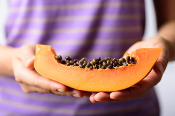 Sliced of ripe papaya fruit with seeds holding by hand, Tropical fruit