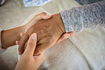 Close up granddaughter takes care of the health sick grandmother at home by holding hands. Lifestyle support the love of the family.