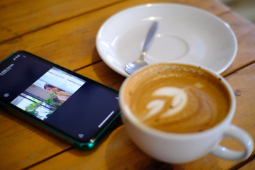 drinks coffee in a cafe(khanom espresso,Thailand) during a meeting. Nearby, a cell phone lies on a table.