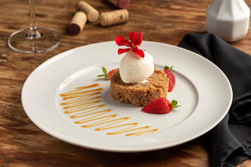 Crumble with ice cream and strawberry, apple on a white plate and blurred background.