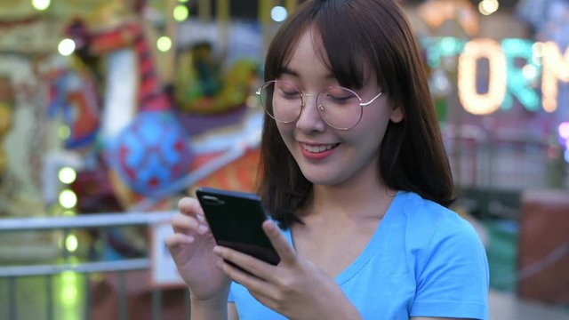 Tourism concept. A girl taking pictures in an amusement park using a mobile phone. 4k Resolution.
