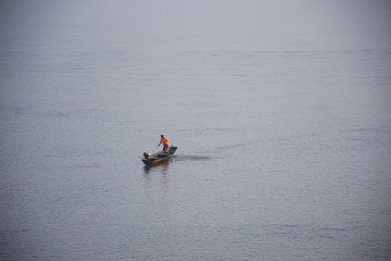 Thai and laos people riding long tail boat for catch fishing and reflection light surface water of Mekhong River and lighting of Sun in morning time at Mukdahan, Thailand