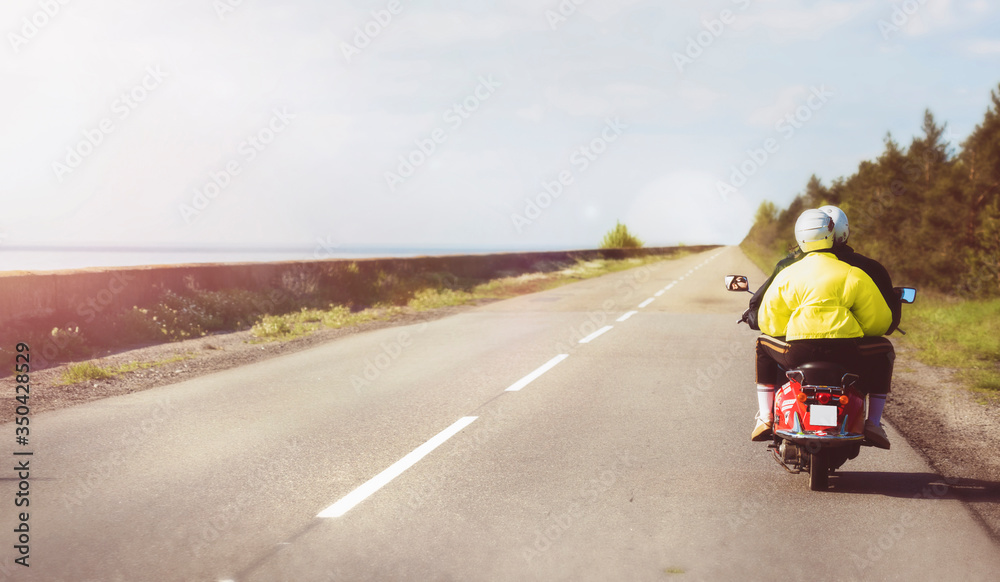 Wall mural travel and active lifestyle concept. couple rides a vintage red motor scooter along the coast