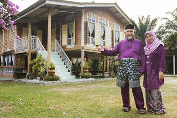 Muslim couple standing outside their house