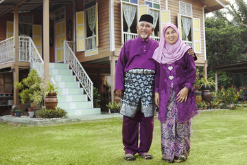 Muslim couple standing outside their house