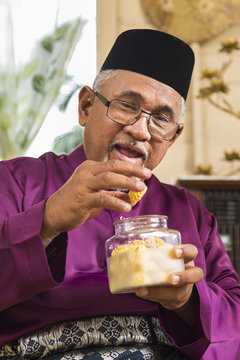 Senior Muslim Man Eating Traditional Malay Cookie