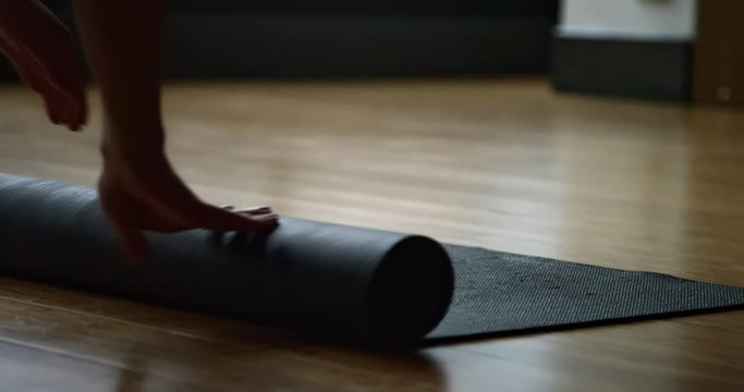 Female yoga student unravels yoga mat in yoga studio getting ready to do a yoga class