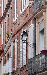 Facades of french houses with shutters on the windows and a wall lantern